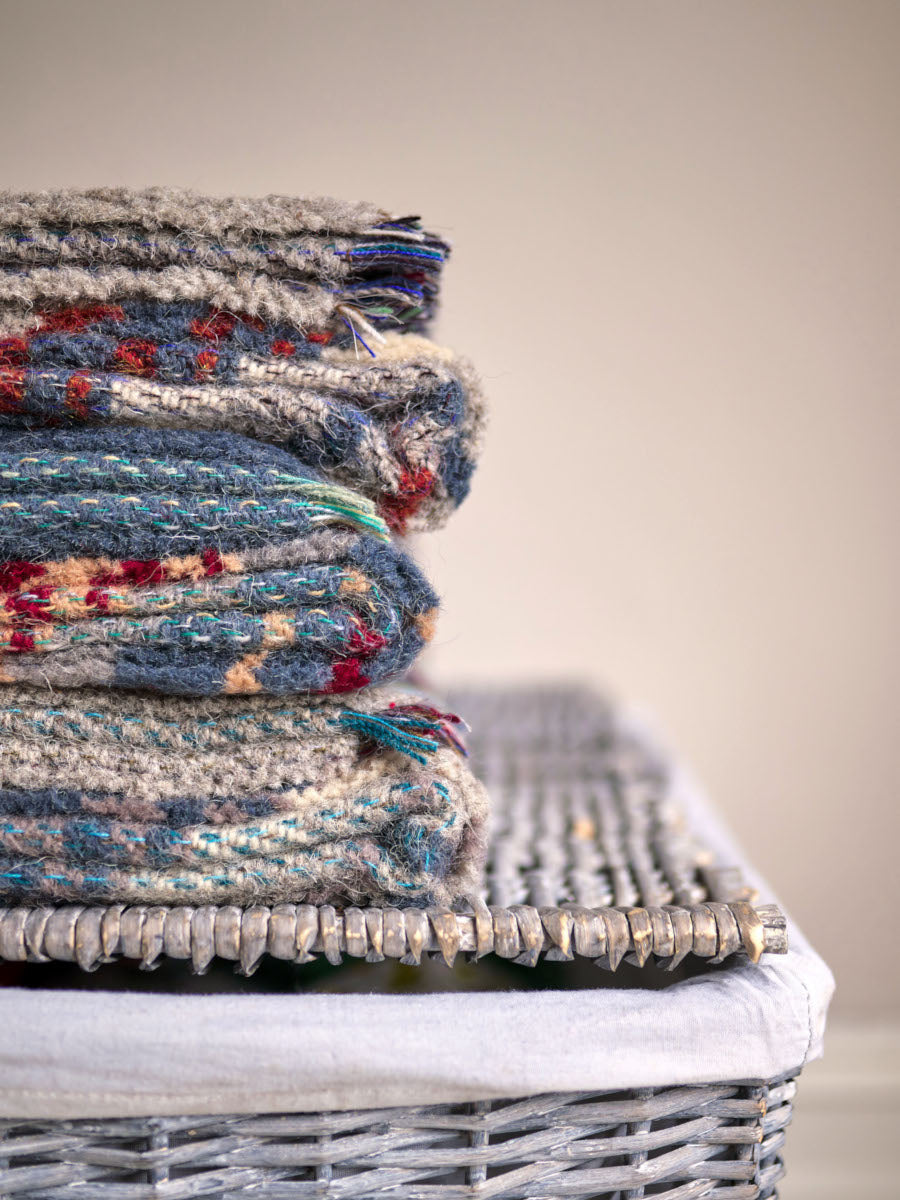 Stack of random recycled rugs on a basket from The British Blanket Company