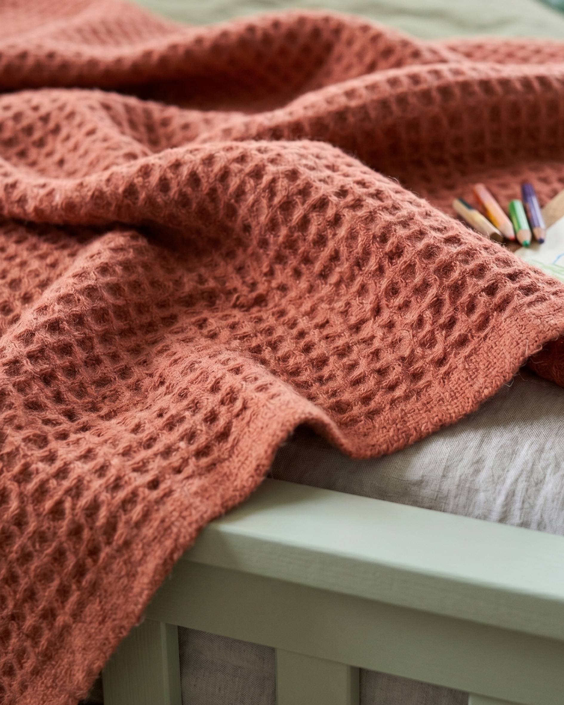 Close up image of terracotta waffle blanket, with children's drawing set