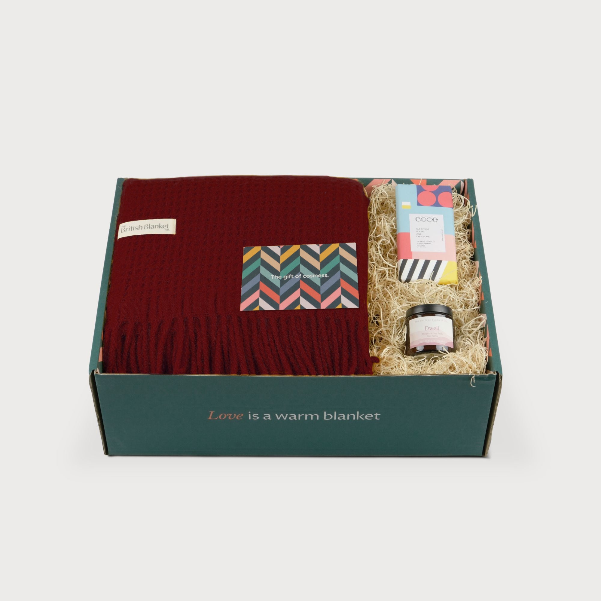 Totterdown Blanket Gift Box: Air Balloon featuring a burgundy woven blanket, colorful greeting card, cocoa bar, and jar, in a green box with a cozy message.