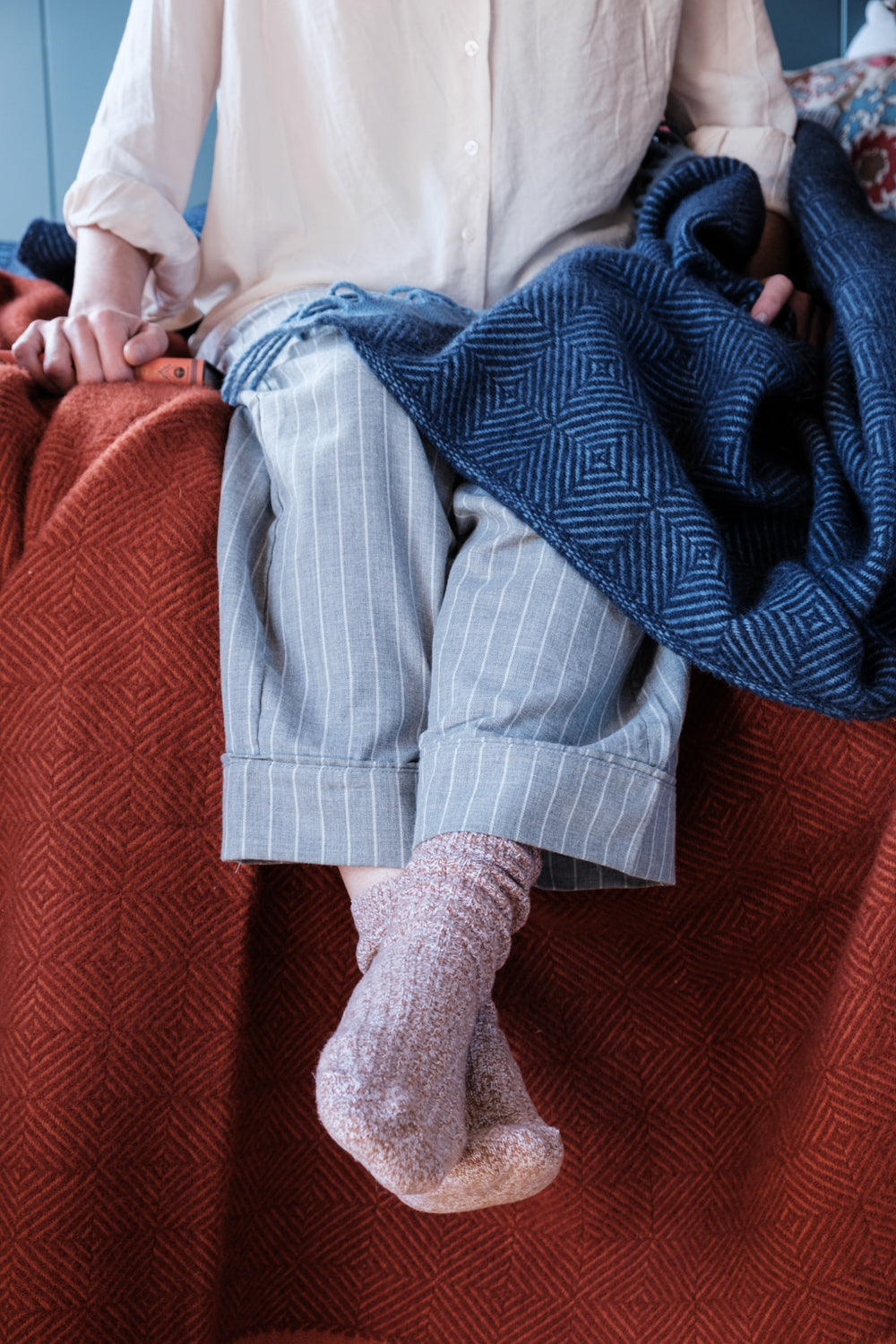 woman sitting on bed with Wildweave wool blankets red and blue