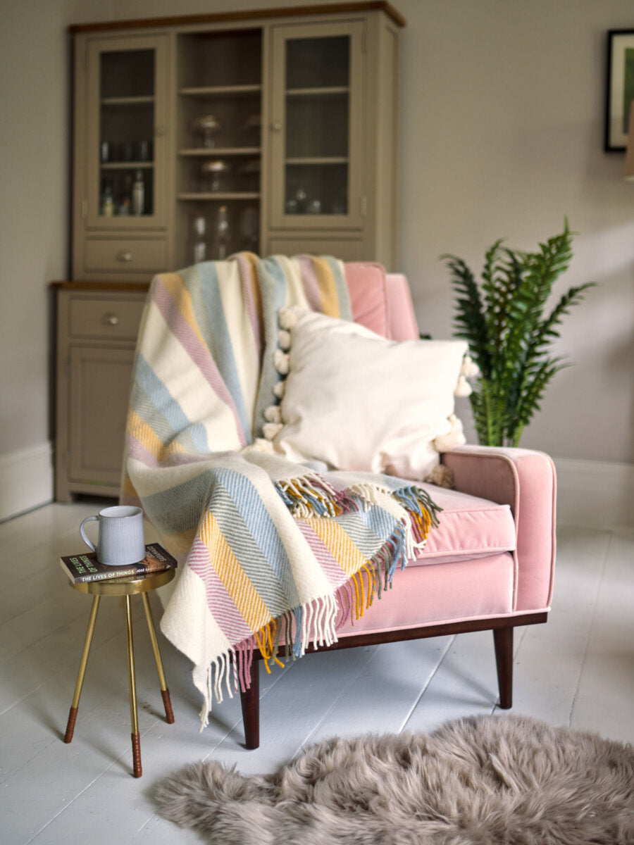 Pink armchair styled with Pastel Rainbow Stripe Herringbone Throw by The British Blanket Company