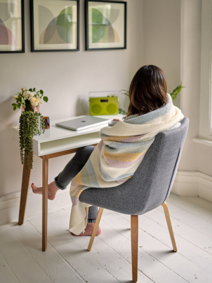 woman at desk in pastel rainbow blanket from The British Blanket Company