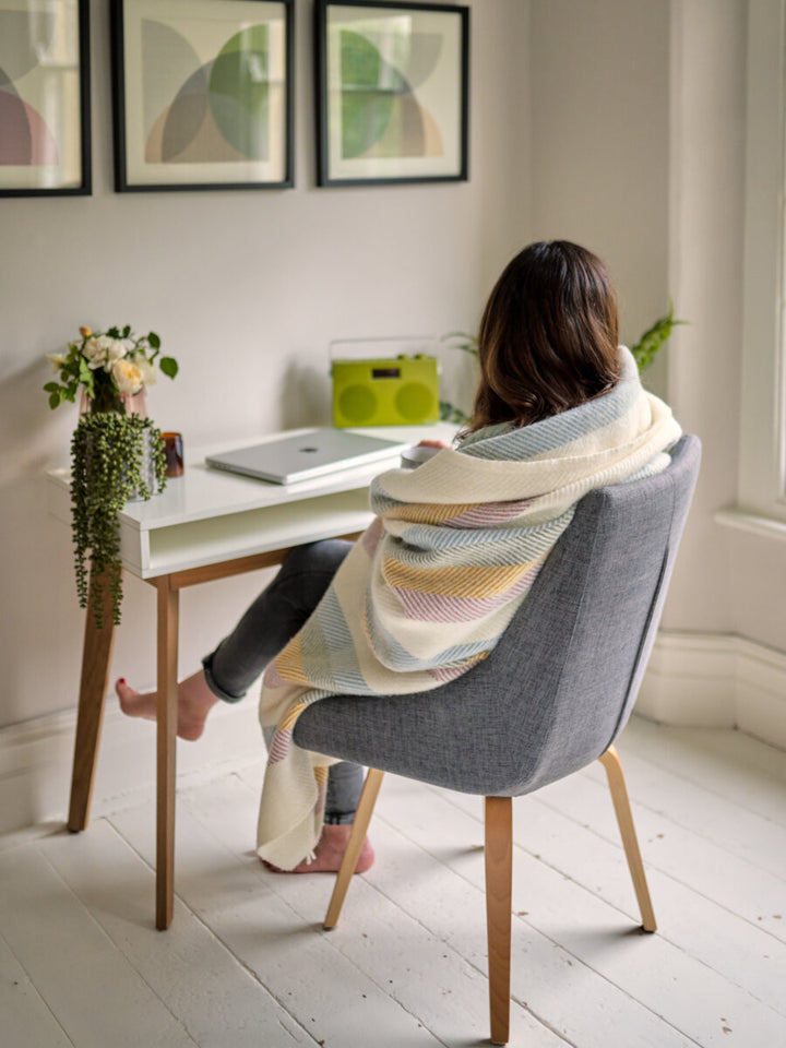 woman at desk in pastel rainbow blanket from The British Blanket Company