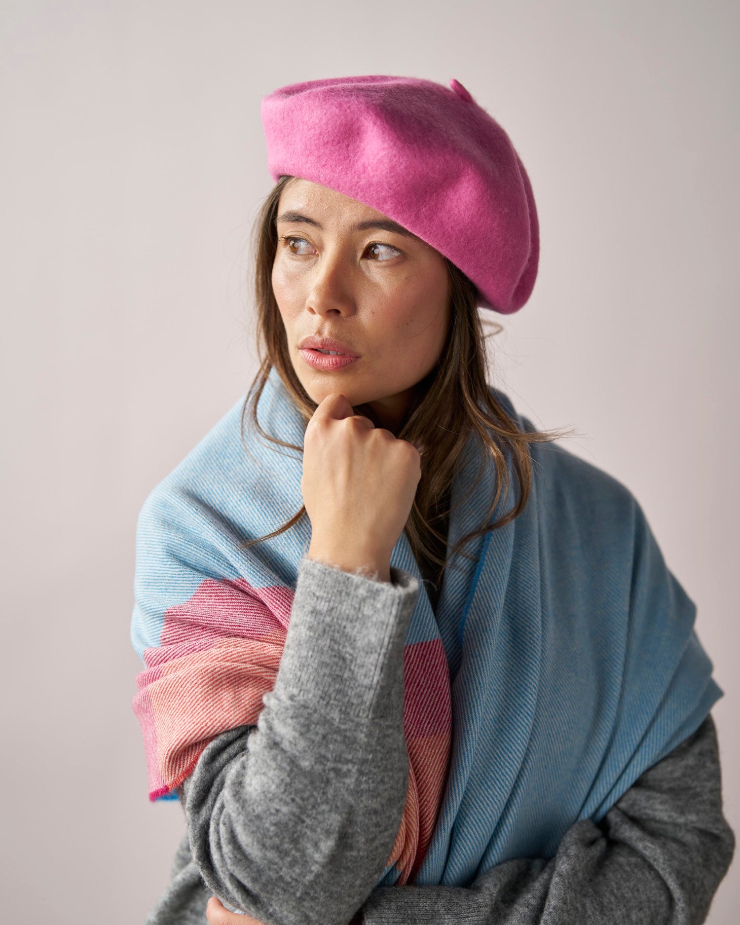 Person wearing a Wool Beret Hat: Pink, styled at an angle. Paired with a gray sweater and pastel scarf, showcasing elegant, cozy fashion.