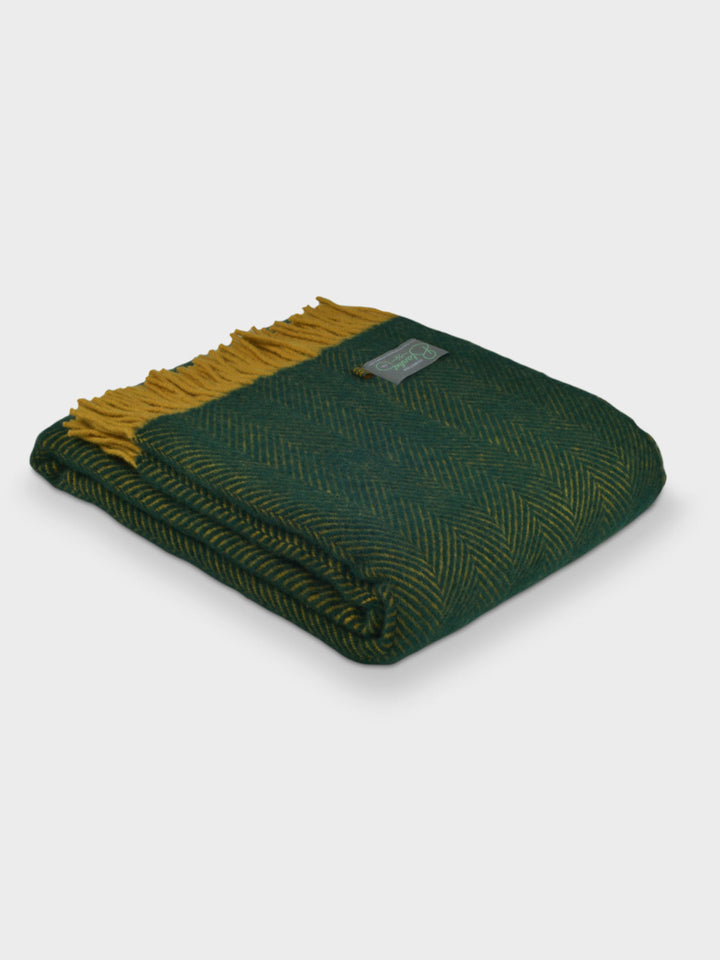 A folded green and yellow herringbone wool throw by The British Blanket Company.