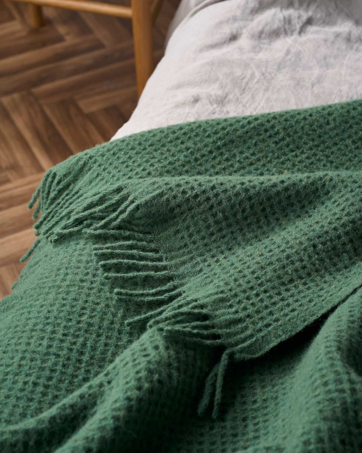 Bright Friday Blanket Bundle: College Green, featuring a textured waffle pattern and loose fringe, draped over a light linen surface with wooden accents in the background.
