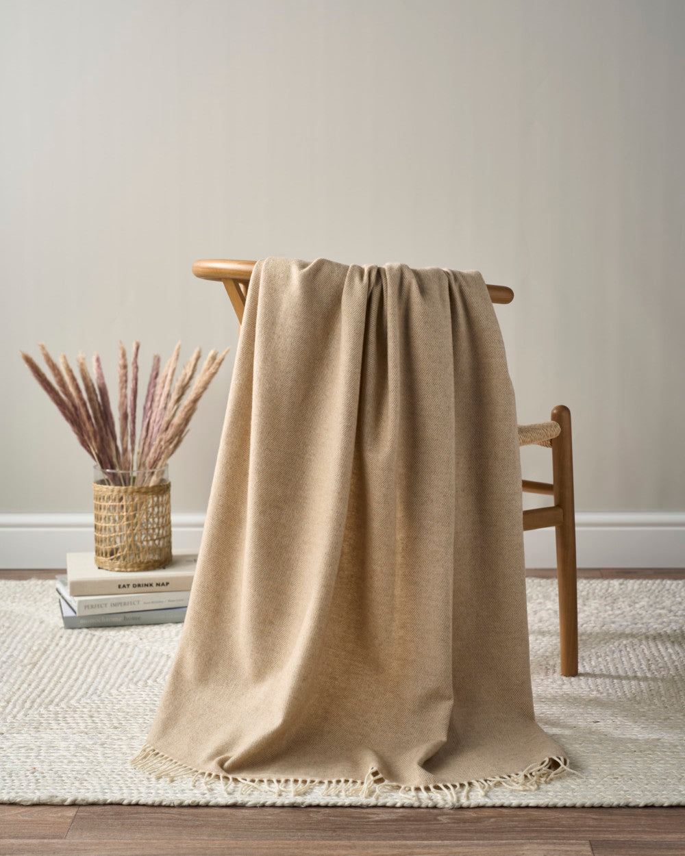 Merino Blanket Gift Box: Basswood; light camel throw on midcentury bench, with books and vase, showcasing minimalist, textural elegance for gifting occasions.