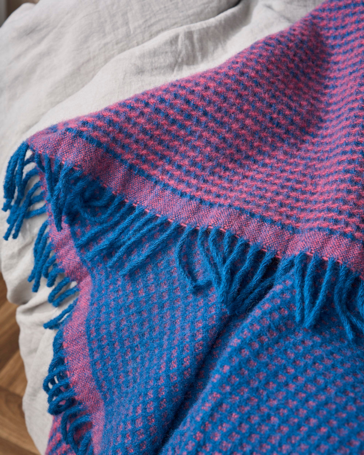 Totterdown Waffle Blanket: Curious & Lush, showcasing a textured waffle weave made from pure wool, displayed on a bed, highlighting its craftsmanship and cozy appeal.