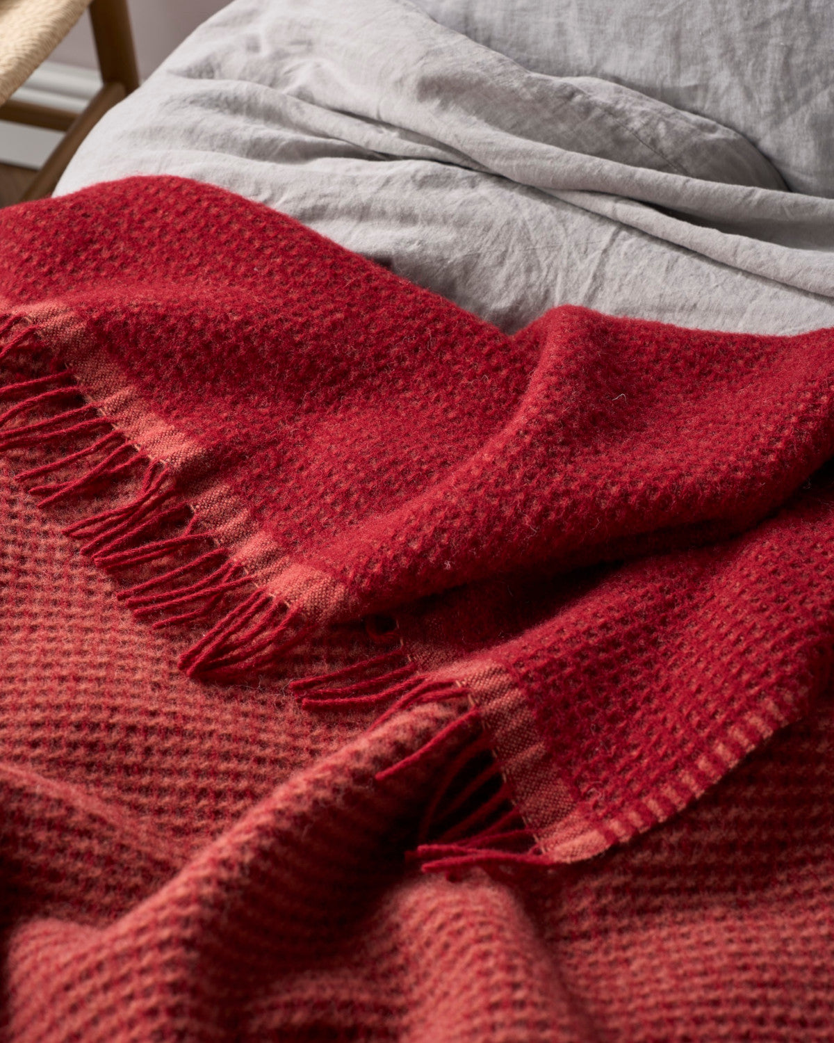 Totterdown Waffle Blanket: Air Balloon & Brunswick, shown on a bed, features a textured waffle weave, crafted from pure wool for a cosy, stylish touch.