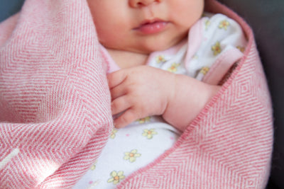 A baby wrapped in a pink merino lambswool baby blanket