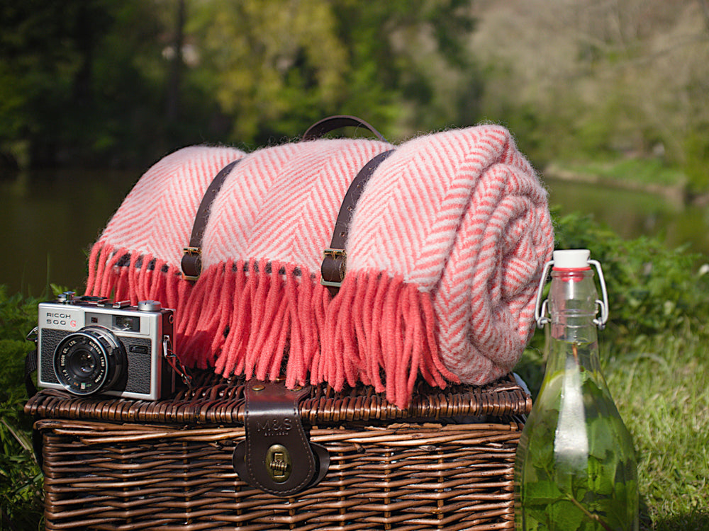Rolled up pink picnic rug on top of a picnic basket. 