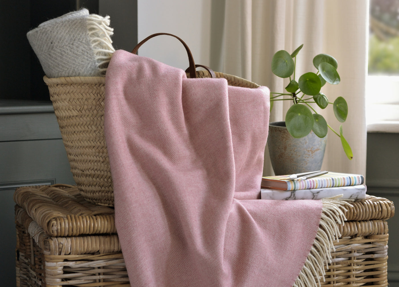 A pink merino wool blanket spilling out of a basket. 