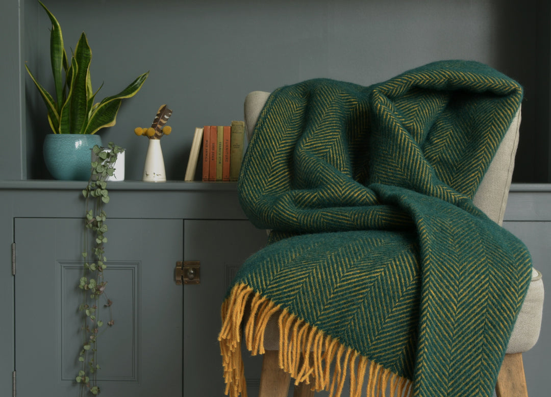 Extra large green and yellow herringbone wool blanket draped over a lounge chair