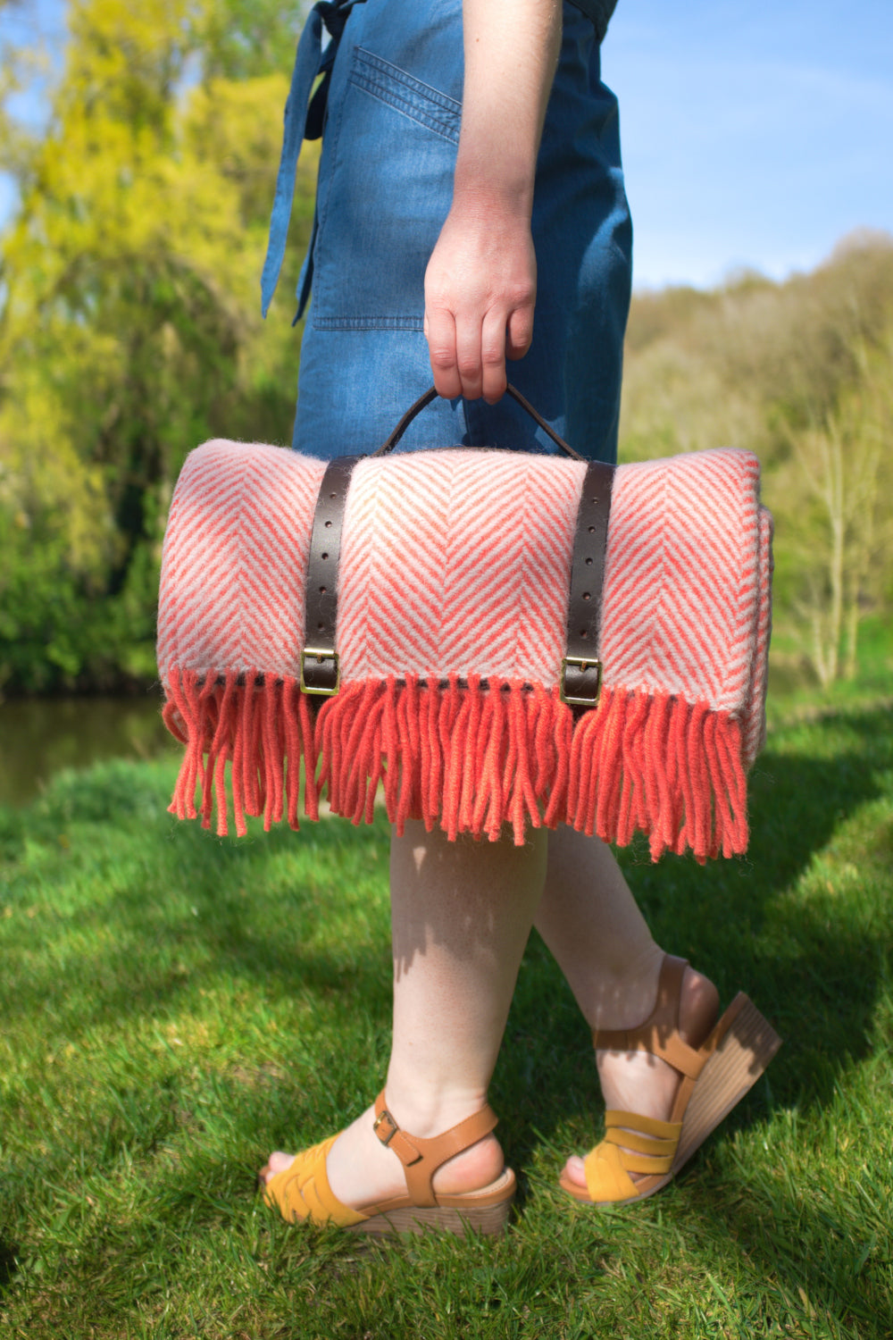 A person holding a rolled up pink wool picnic rug.