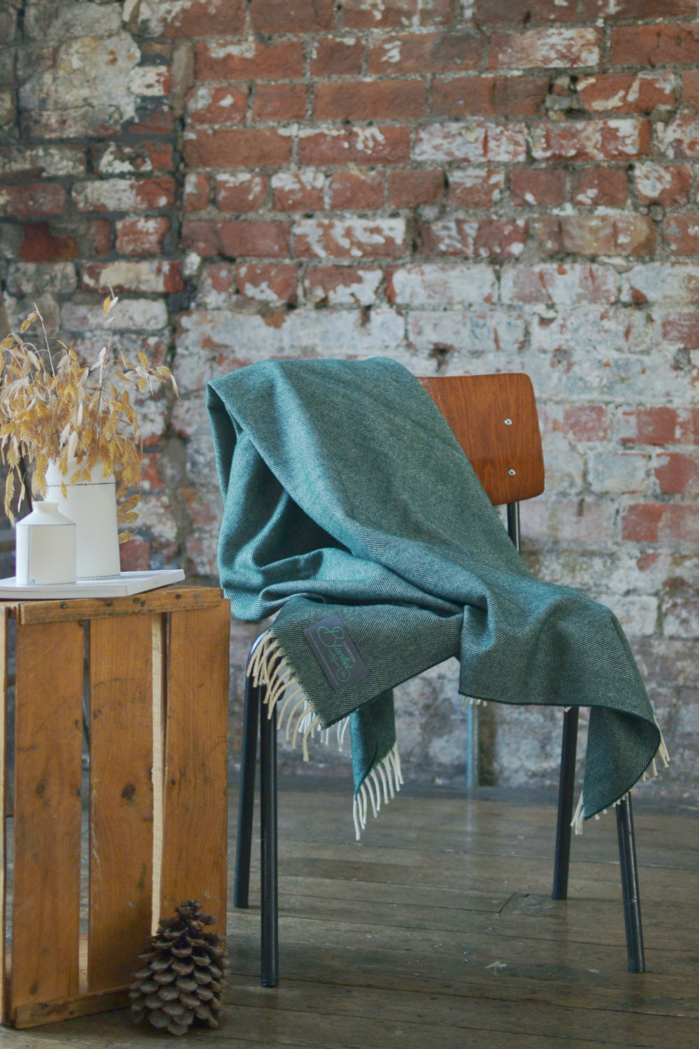 Green herringbone wool blanket draped over wooden chair. 