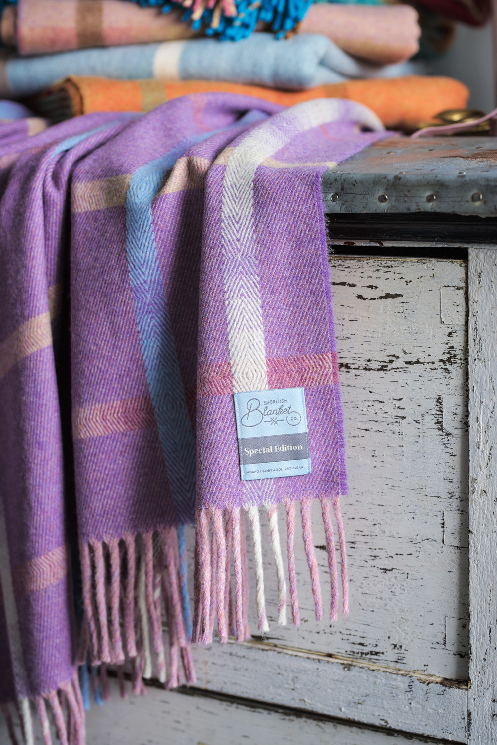 Large purple merino lambswool blanket draped over a chest of drawers