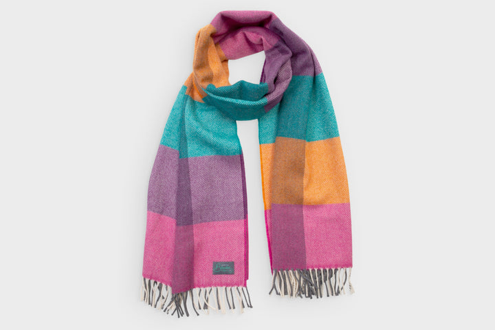 Multicoloured oversized lambswool scarf by The British Blanket Company. The scarf is pink, purple, blue, and yellow coloured.