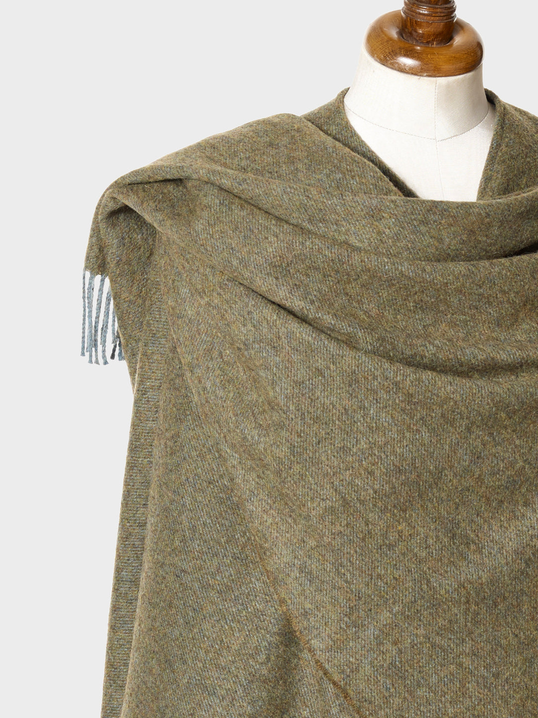 Closeup of a green wearable lambswool blanket wrap on a mannequin
