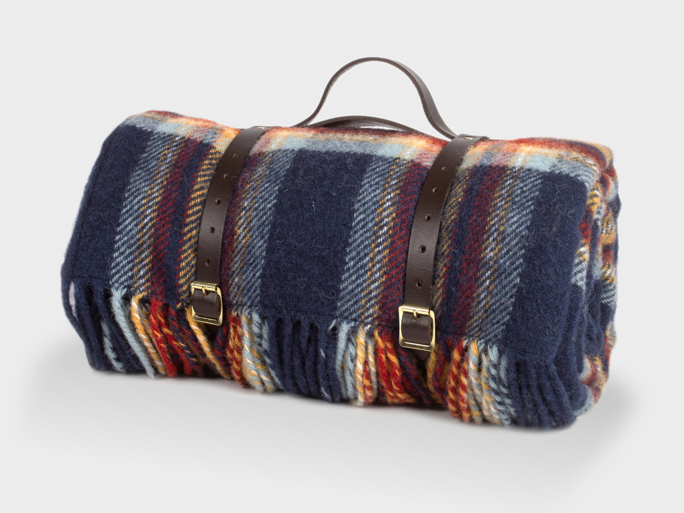 Multi-coloured picnic rug by The British Blanket Company rolled up with leather straps.