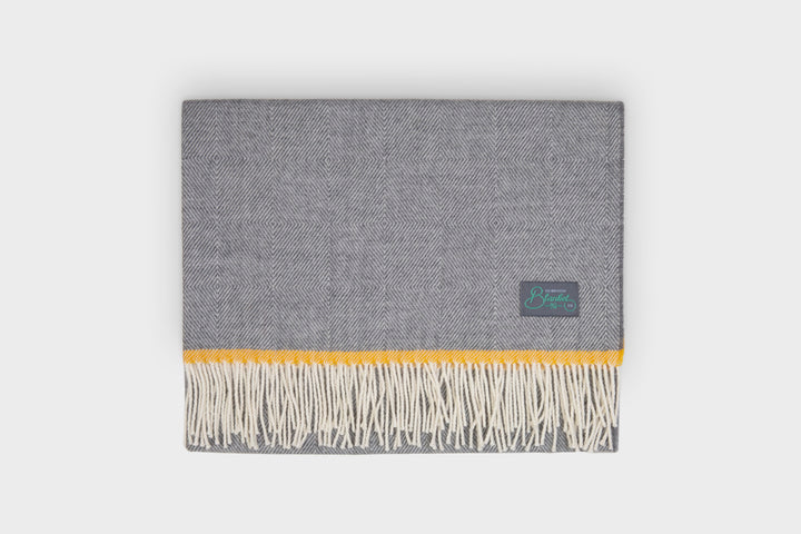 A folded grey and yellow wool baby blanket by The British Blanket Company.