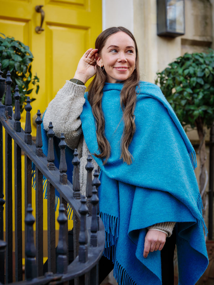 A woman wearing a blue wearable lambswool blanket wrap 