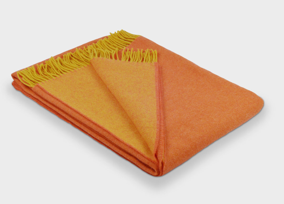 Folded orange and yellow reversible merino wool throw by The British Blanket Company
