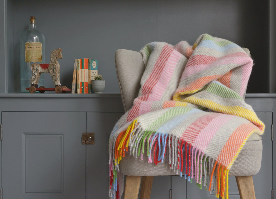 Extra large rainbow herringbone wool blanket draped over a lounge chair