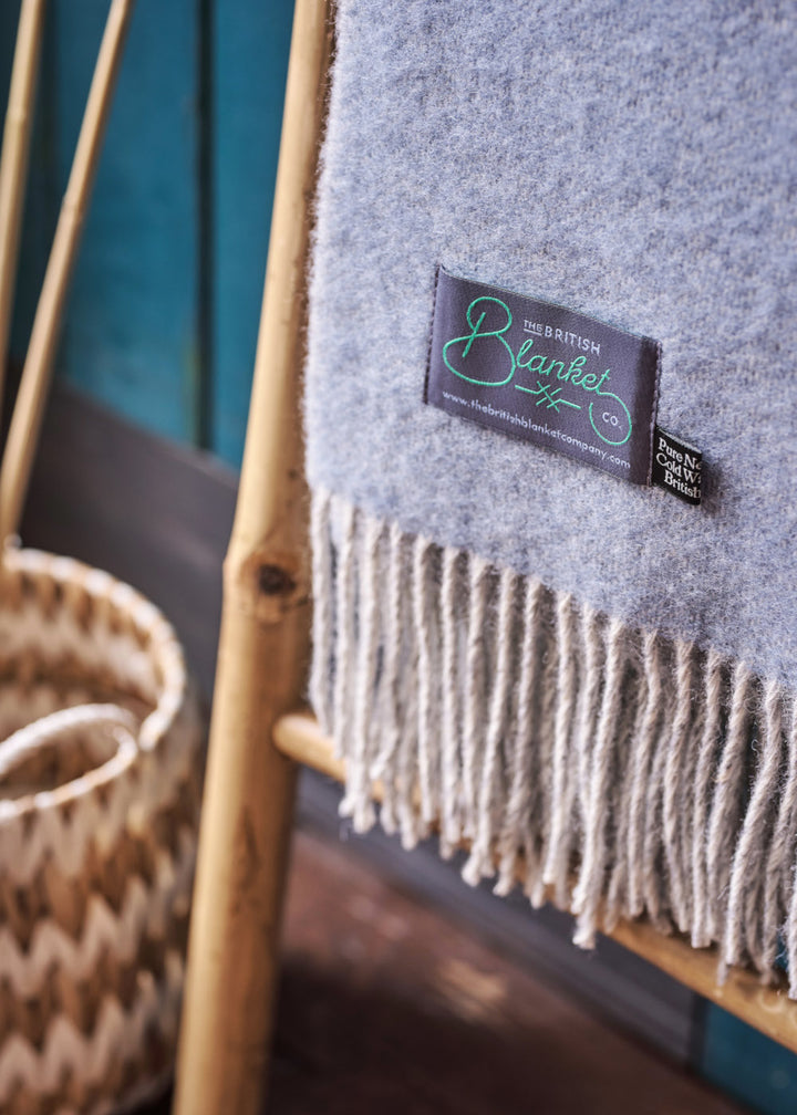 blue and grey reversible wool throw blanket by The British Blanket Company hanging on a bamboo ladder