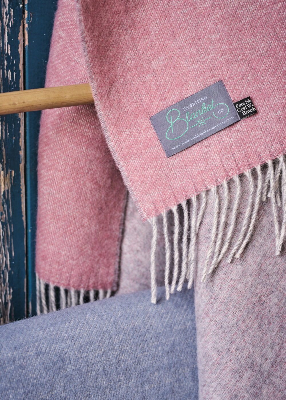 Corner of a pink and grey reversible wool throw blanket by The British Blanket Company