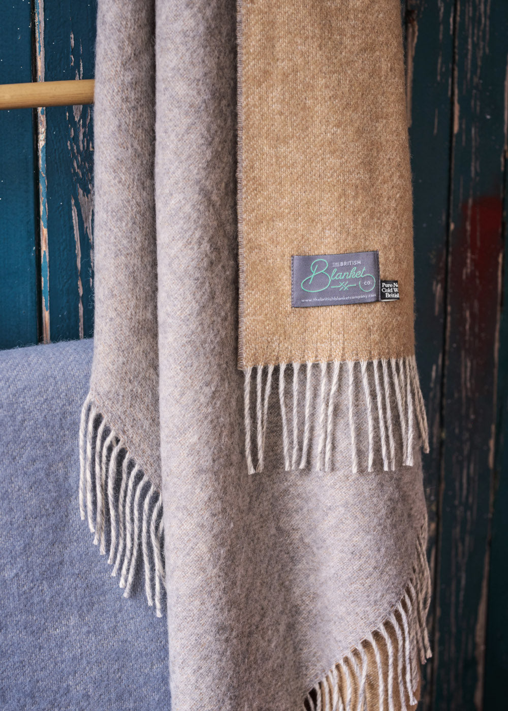Corner of a folded sand brown and grey reversible wool throw blanket by The British Blanket Company