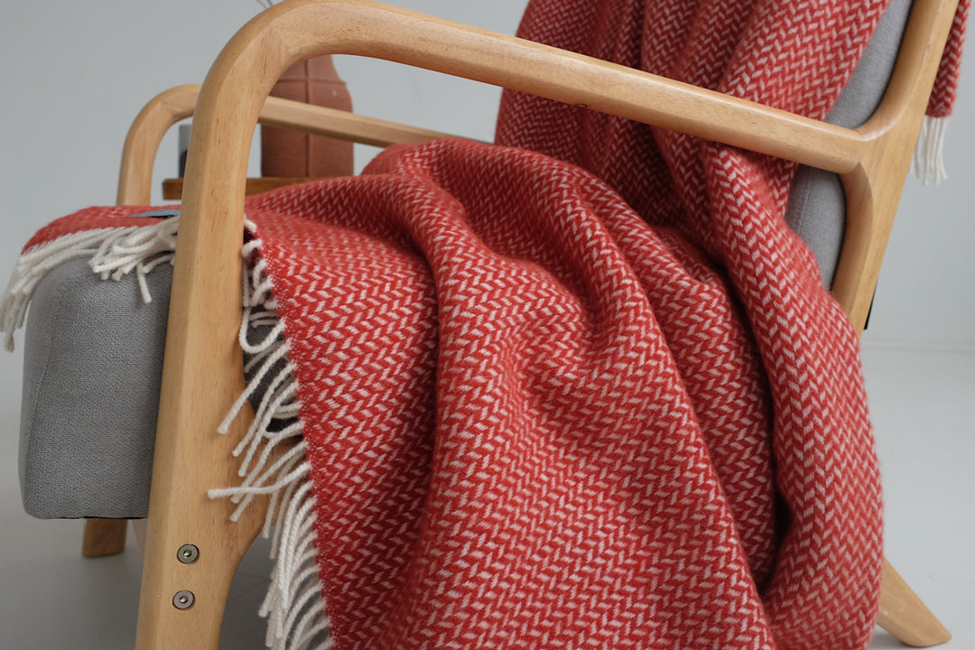 Red herringbone wool blanket draped over a lounge chair