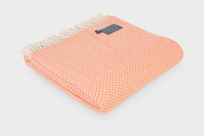 Large folded orange herringbone wool throw by The British Blanket Company.