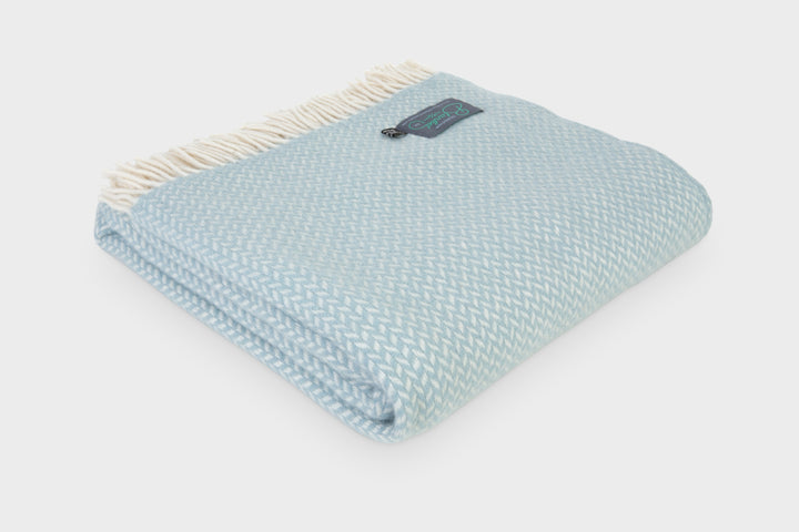 A folded duck egg blue herringbone wool throw by The British Blanket Company.