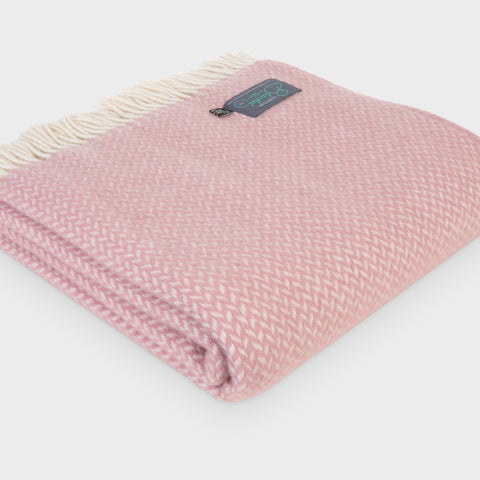 Large folded pink herringbone wool throw by The British Blanket Company.