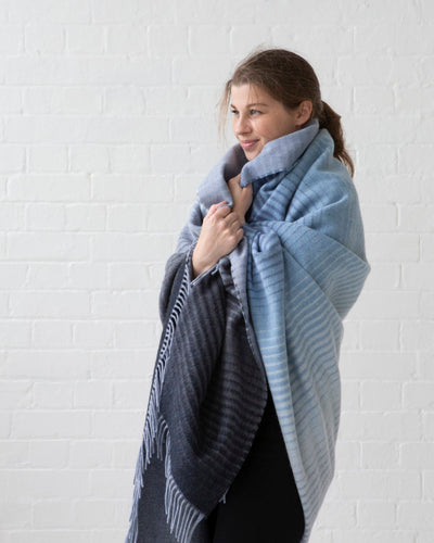 A woman wrapped in large blue ombre merino wool blanket