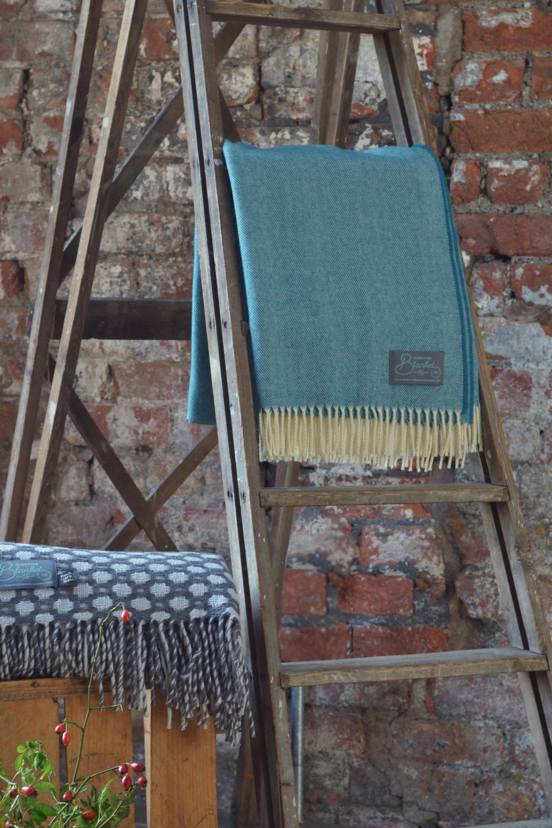 Large teal merino herringbone blanket hanging on a wooden ladder