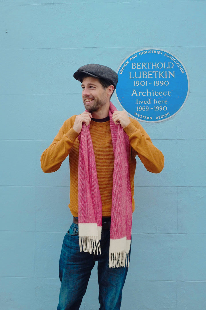 A man holding a red herringbone lambswool scarf over his neck