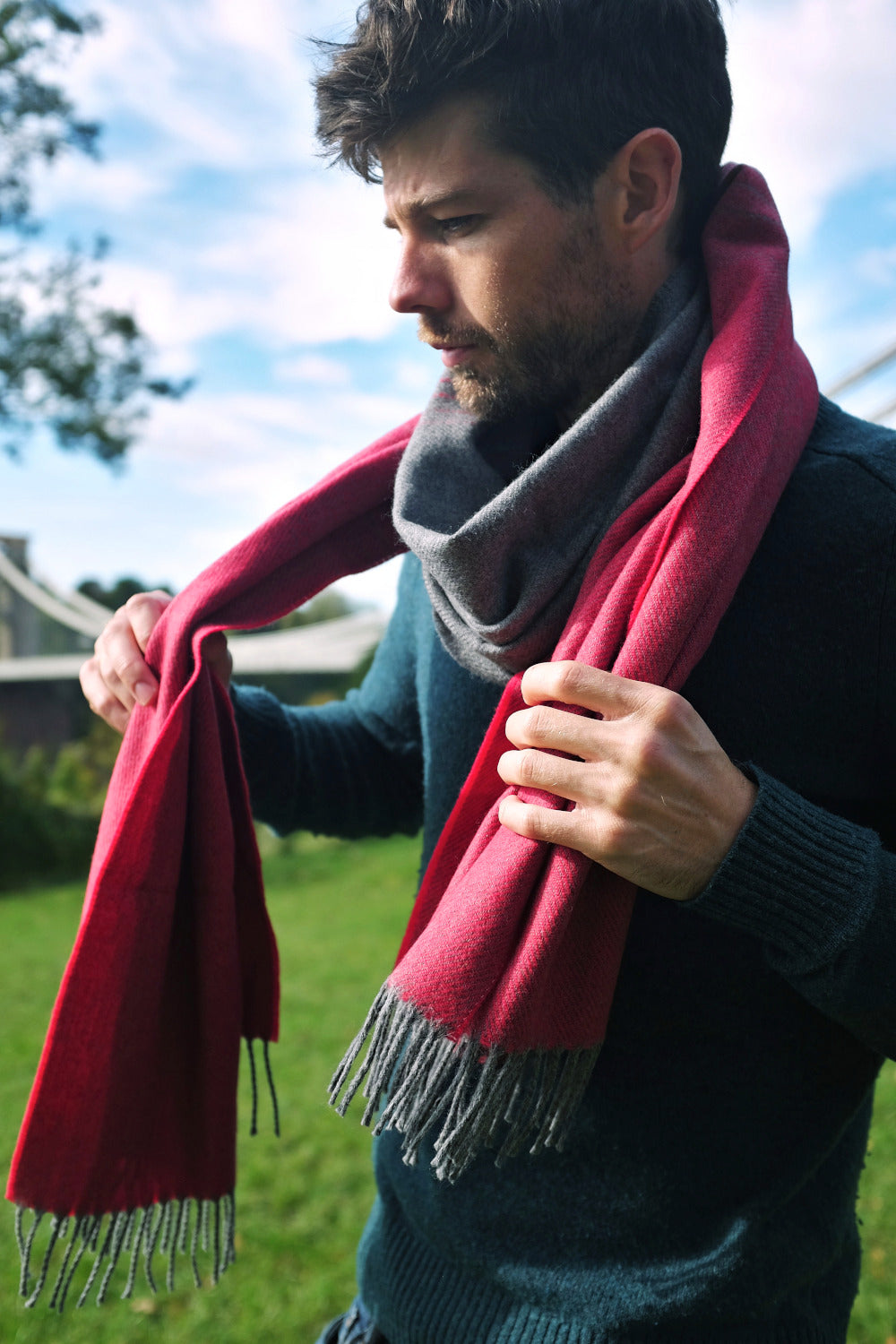 A man holding a red and grey oversized blanket scarf hanging across his shoulders