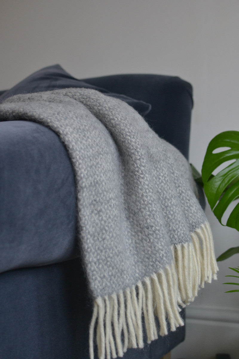Large grey windmill wool blanket draping over the side of a sofa