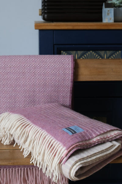 A folded pink ombre merino wool blanket on a wooden chair