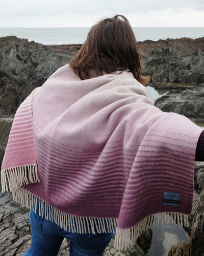 A woman wrapped with a large pink ombre merino wool throw