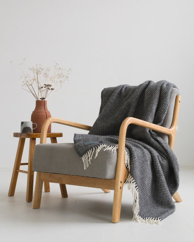 A large grey wool blanket draped over a lounge chair. 