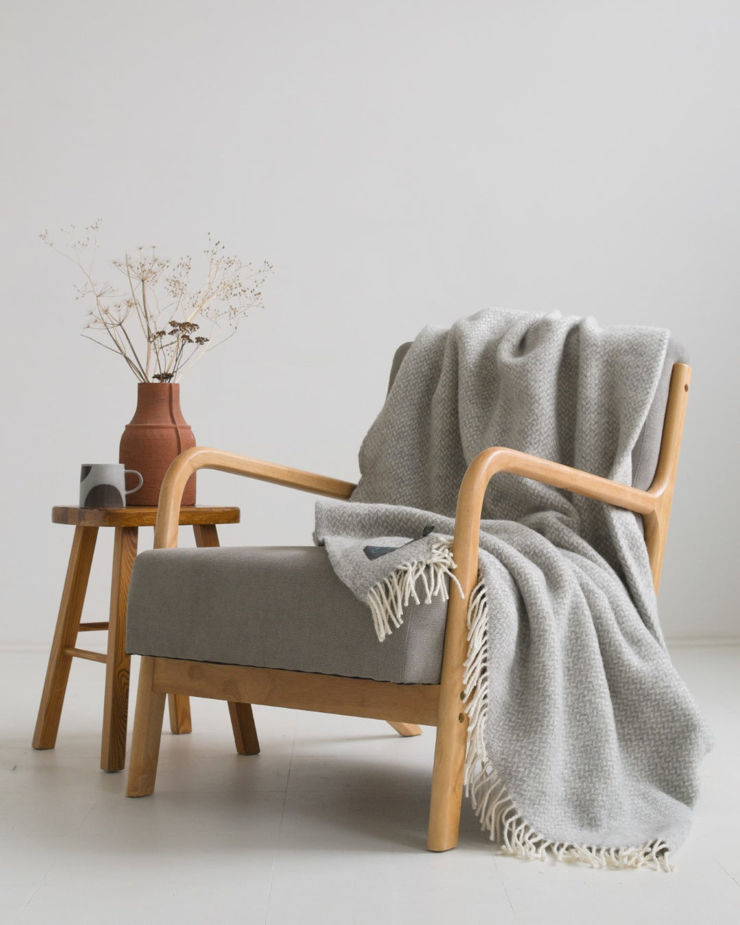A large silver grey herringbone wool blanket draped over a lounge chair
