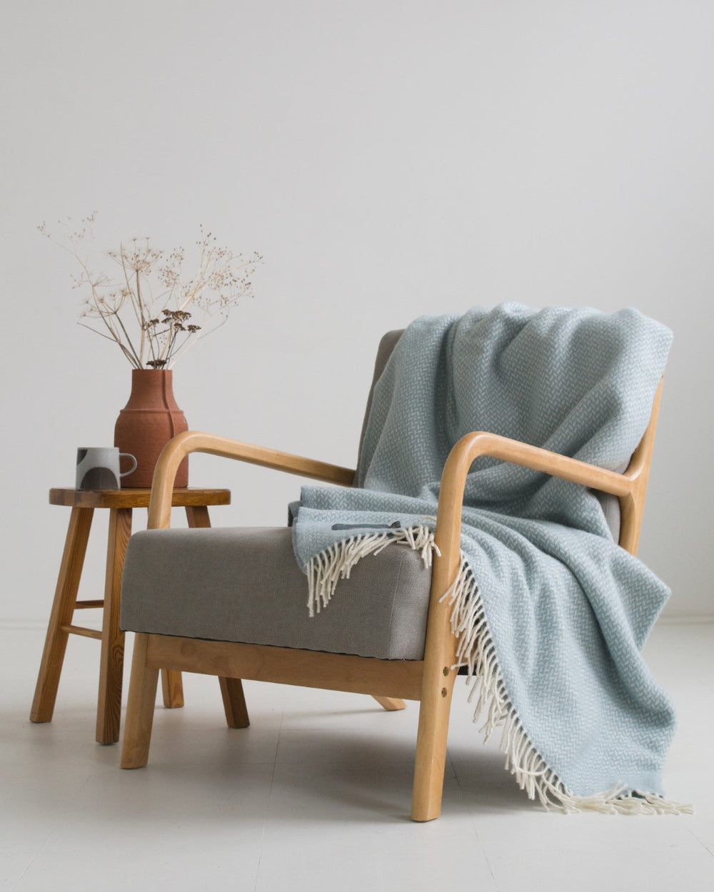 Extra large blue herringbone wool blanket draped over a lounge chair