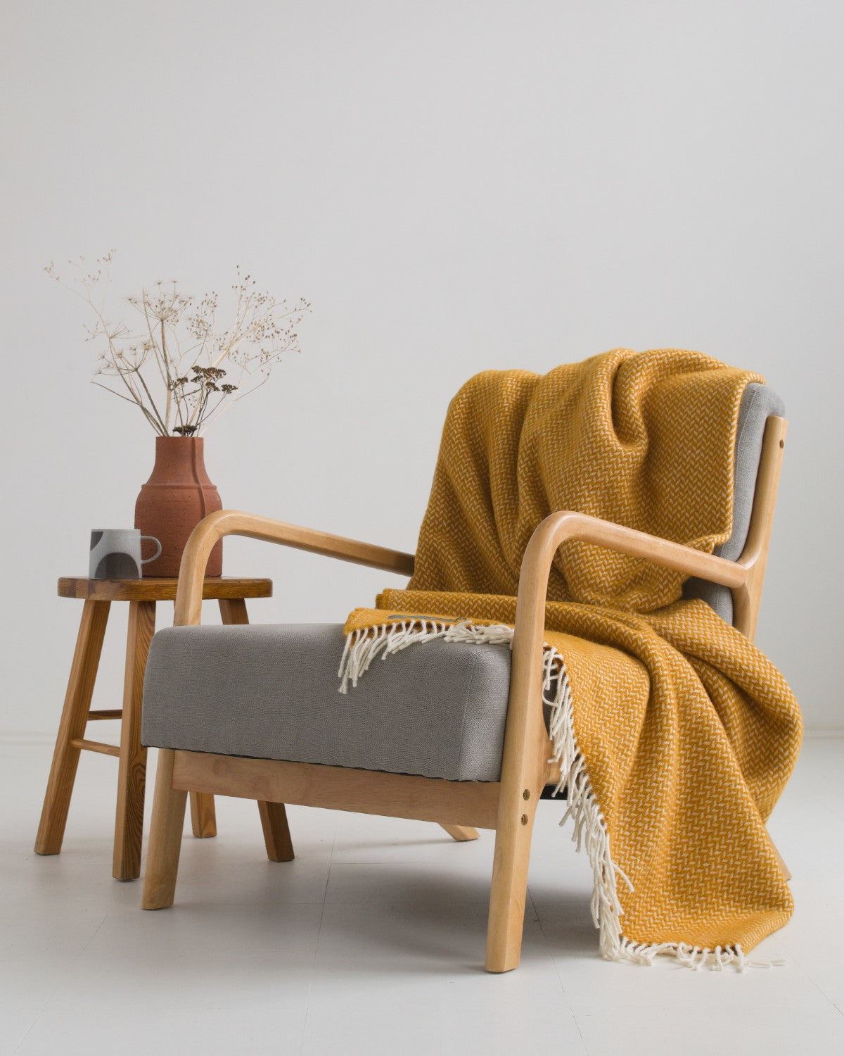 Extra large yellow herringbone wool blanket draped over a lounge chair