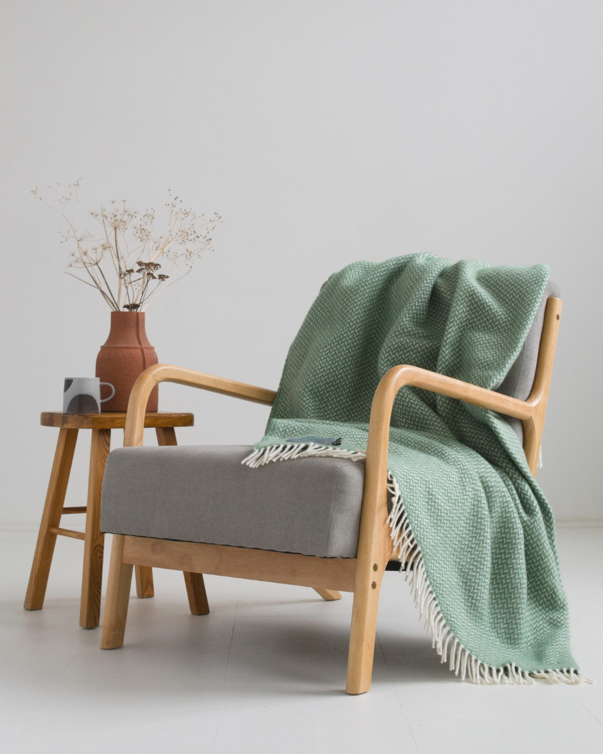 Large green herringbone wool blanket draped over a lounge chair