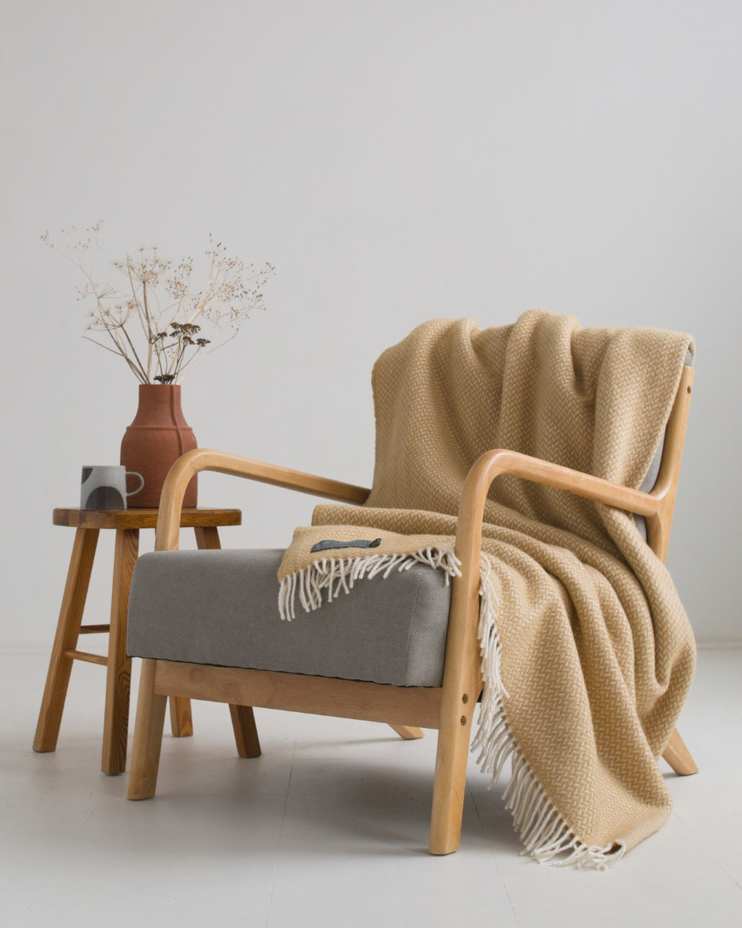 A large toffee herringbone wool blanket draped over a lounge chair