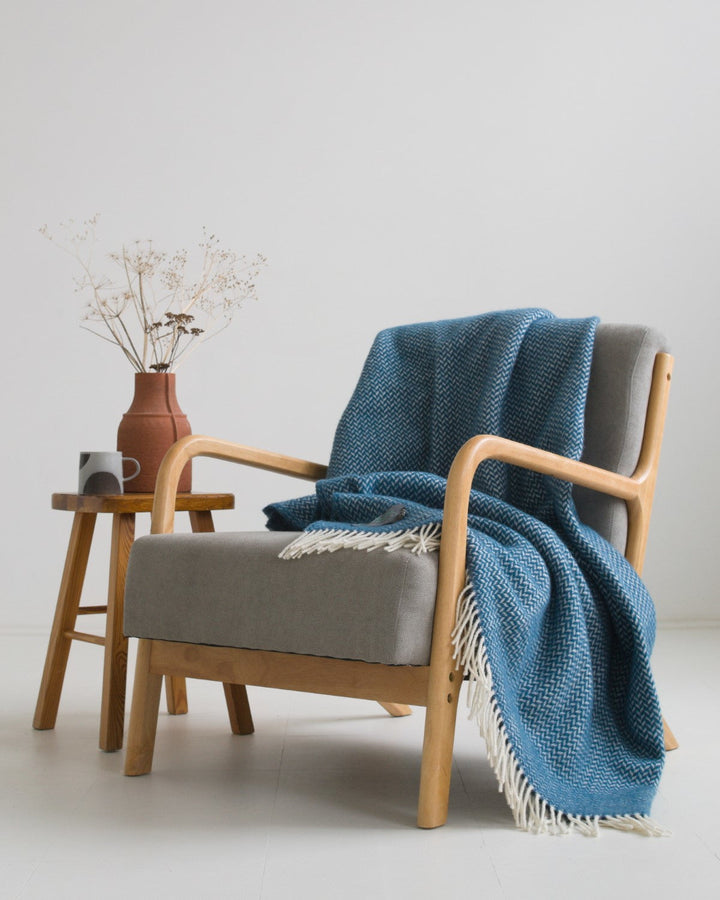 Extra large blue herringbone wool blanket draped over a lounge chair