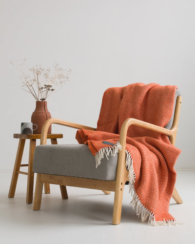 Extra large orange herringbone wool blanket draped over a lounge chair