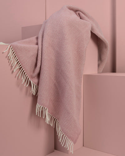 Pink herringbone wool throw draped over display plinths.
